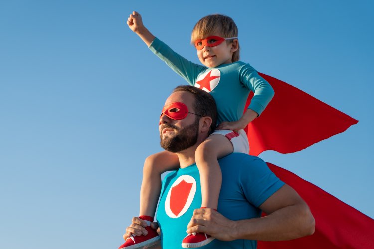 Abbildung: Grusskarten Vatertag - Vater und Sohn sind als Supermann verkleidet, Sohn sitzt auf den Schultern des Vaters